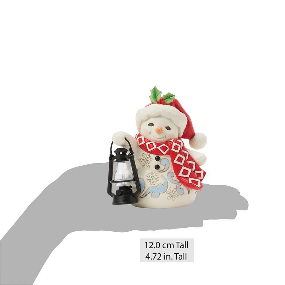Sneeuwpopfiguurtje met rode sjaal en muts, die een lantaarn vasthoudt; versierd met sneeuwvlokken.
