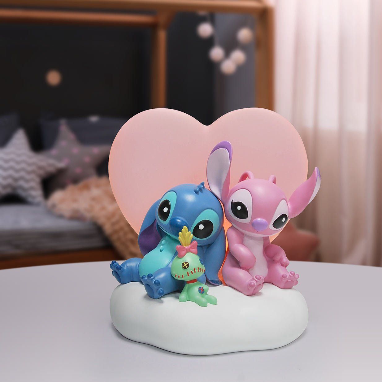 De figuren Stitch en Angel zitten op een wolk met een hartvormige achtergrond, die verlicht is.
