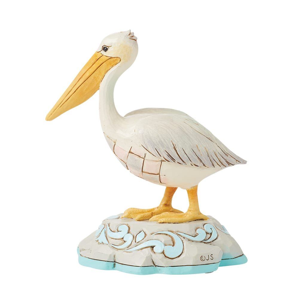 Beeldje van een witte pelikaan met gele snavel en poten, zittend op een decoratieve sokkel met blauwe accenten.