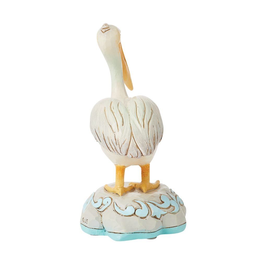 Een beeldje van een witte pelikaan, staand op een wolkvormige sokkel.