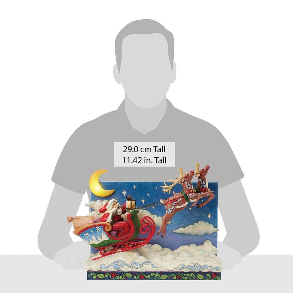 De kerstman in zijn slee, getrokken door een rendier, vliegt door een nachtelijke hemel met maan en wolken.