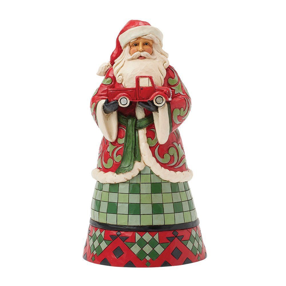 Een kerstmanfiguur met een rode vrachtwagen. Hij draagt een rode jas met groene en witte details over een groen-rood gestreepte rok.