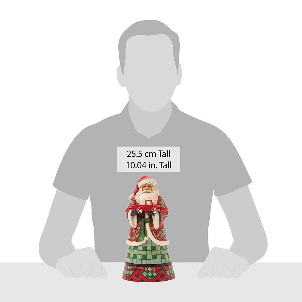 Een kerstmanfiguur met een rode vrachtwagen. Hij draagt een rode jas met groene en witte details over een groen-rood gestreepte rok.