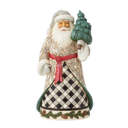 Een kerstmanfiguur met een kerstboom in zijn handen, gekleed in een jas met patroon, een rode sjerp en een grijze muts.