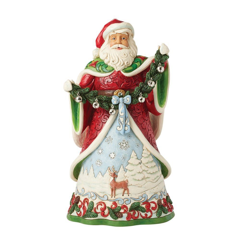 Standbeeld van de Kerstman in een rode mantel, met een kerstkrans in zijn hand. Op de sokkel staan herten en besneeuwde bomen.