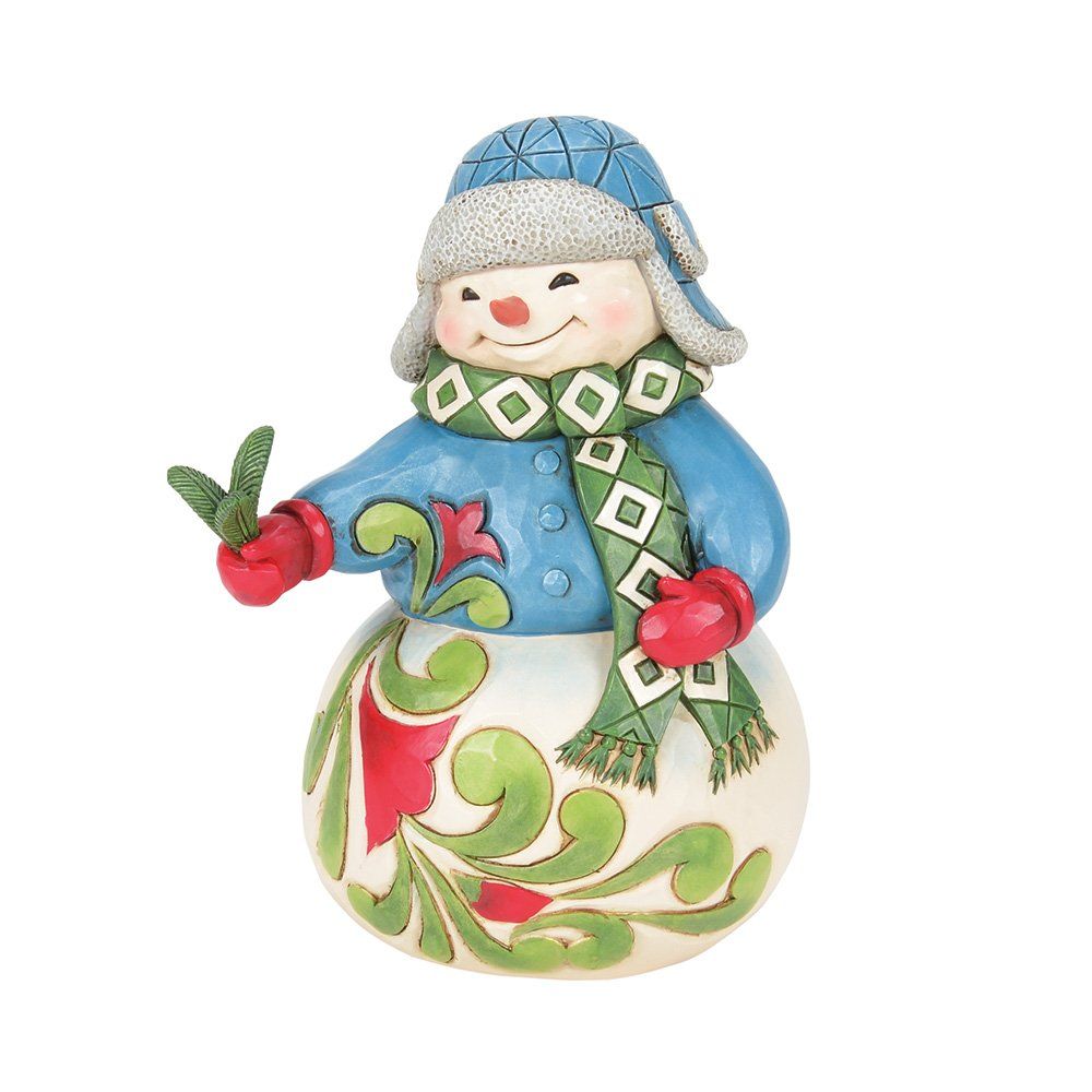 Sneeuwpopfiguurtje met een blauwe muts, jas, groene sjaal, rode wanten en een versierde voet met een bloemenmotief.