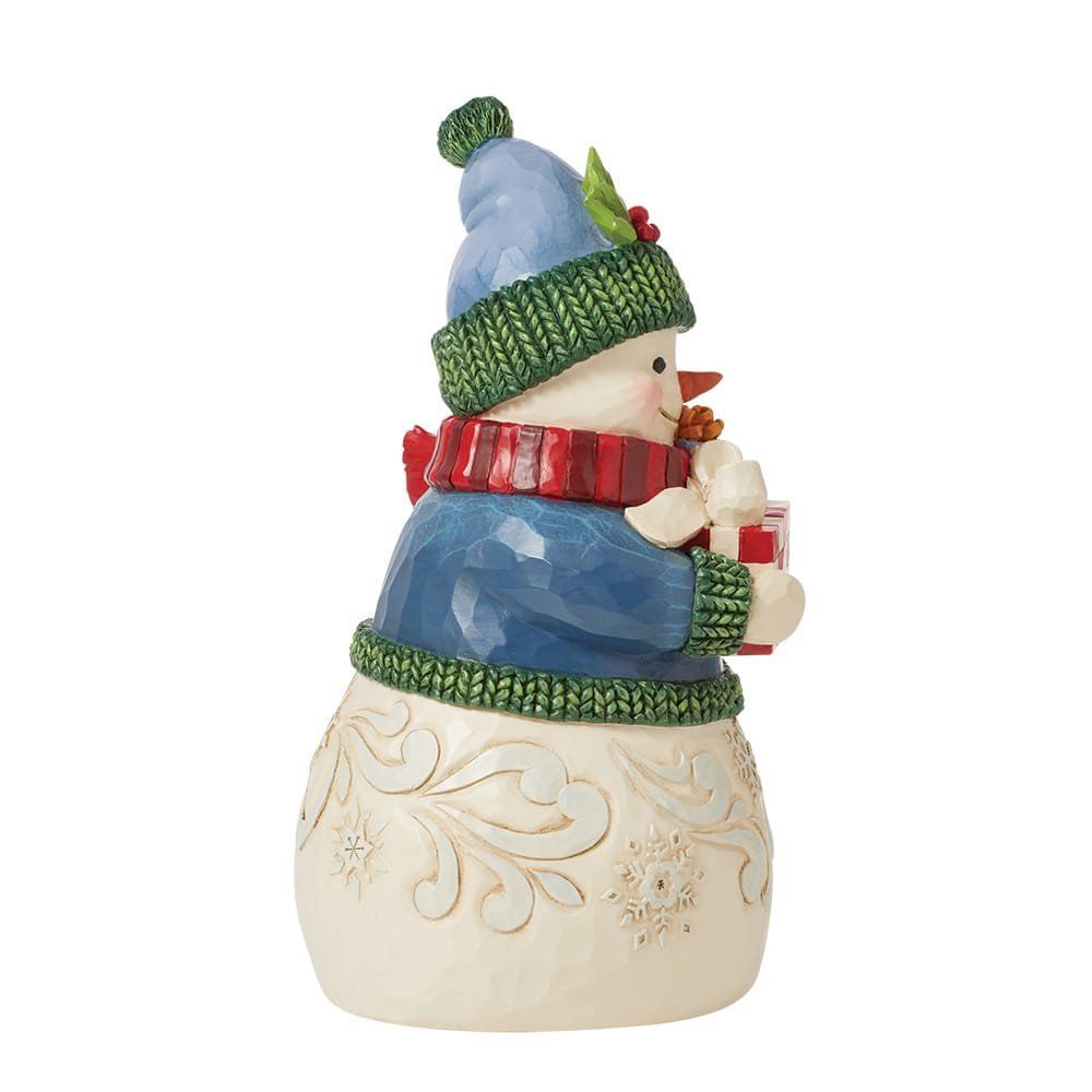 Een sneeuwpopfiguurtje dat een cadeautje vasthoudt, een blauwe muts, sjaal en trui draagt.