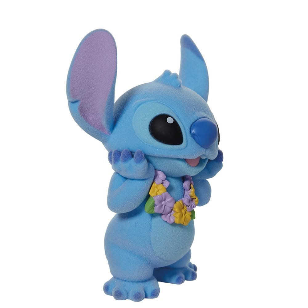 Een figuurtje van Blue Stitch met een bloemenkrans om, de handen omhoog en een lachend gezicht.