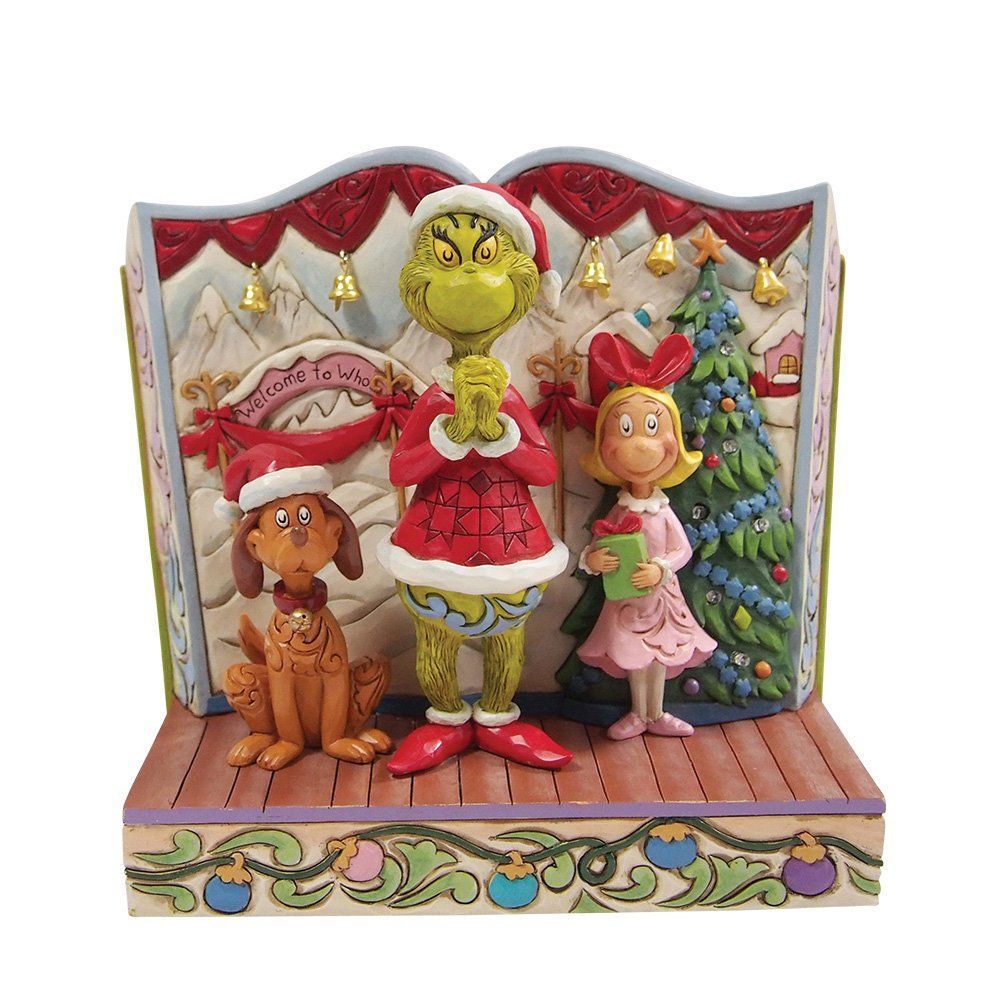 Figuurtjes van de Grinch, Max en Cindy Lou Who op een podium, met een kerstboom en rode versieringen.
