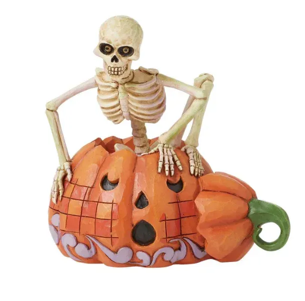 Een skelet dat uit een uitgeholde oranje pompoen tevoorschijn komt.