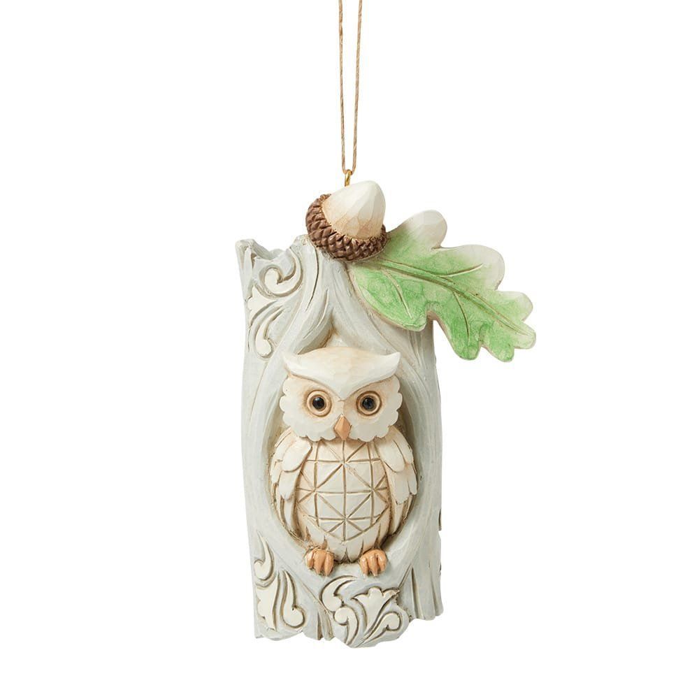 Een uilenornament in een boomholte met een eikel en een blad, hangend aan een touwtje.