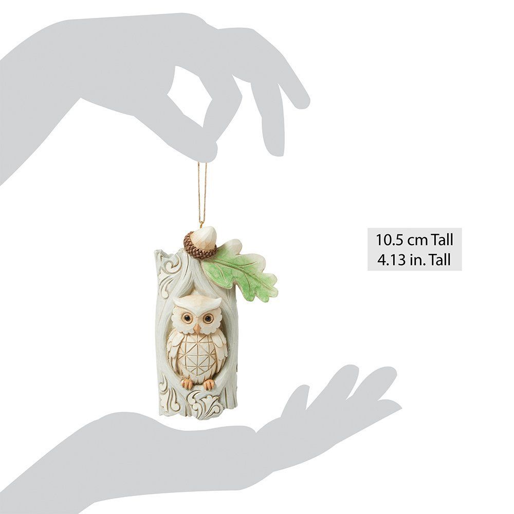 Een uilenornament in een boomholte met een eikel en een blad, hangend aan een touwtje.