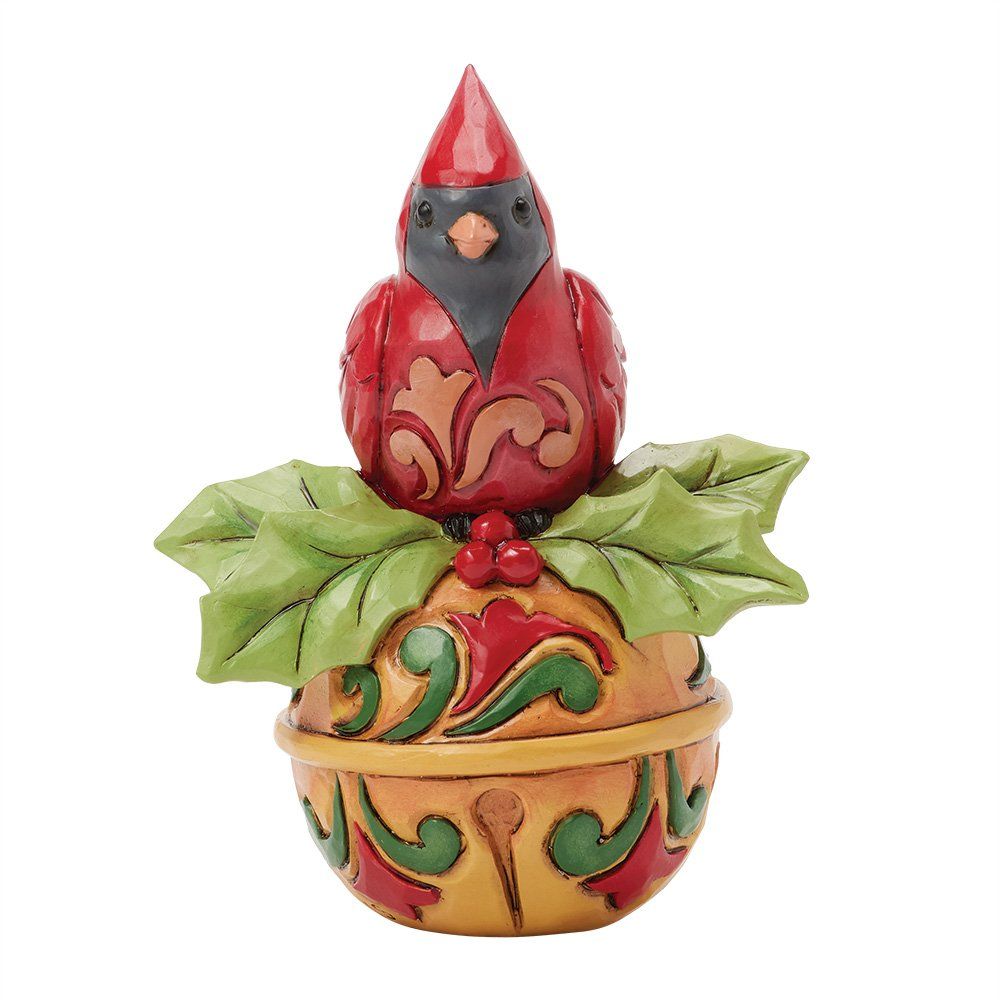Een beeldje van een rode kardinaal, geplaatst bovenop een decoratief ornament met hulstbladeren.