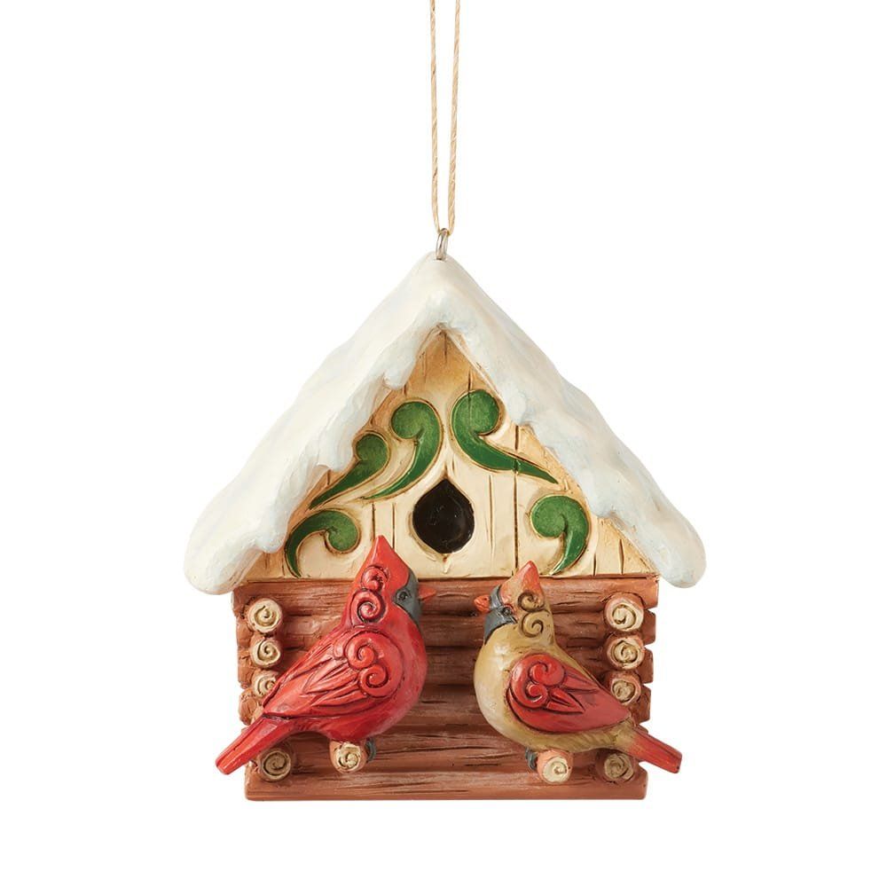 Decoratie met kardinaalvogels; rode en beige vogels op een vogelhuisje in de vorm van een blokhut.