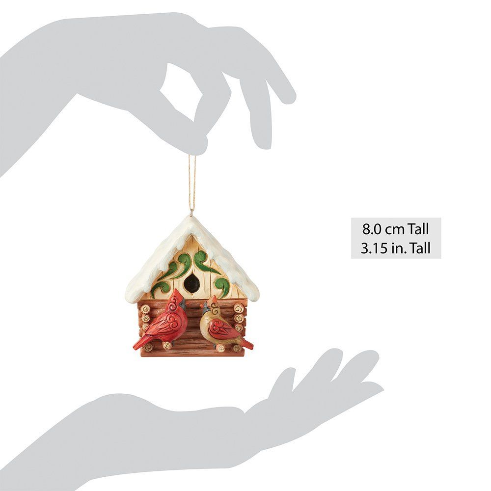 Decoratie met kardinaalvogels; rode en beige vogels op een vogelhuisje in de vorm van een blokhut.