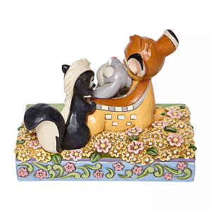 Een Bambi-figuurtje met Stampertje en Bloem op een doos met bloemen- en bladmotieven.