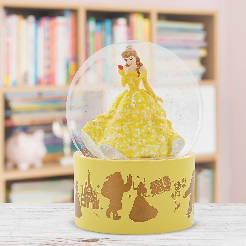 Sneeuwbol met Belle, die een rode roos vasthoudt, een gele jurk, een gele voet met filmscènes en een boekenplank op de achtergrond.
