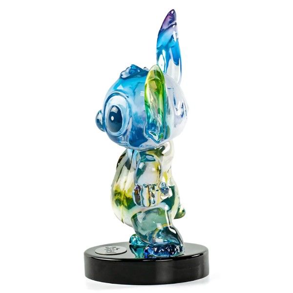 Een Stitch-figuurtje in blauwe en gele tinten, in een pose op een zwarte sokkel.