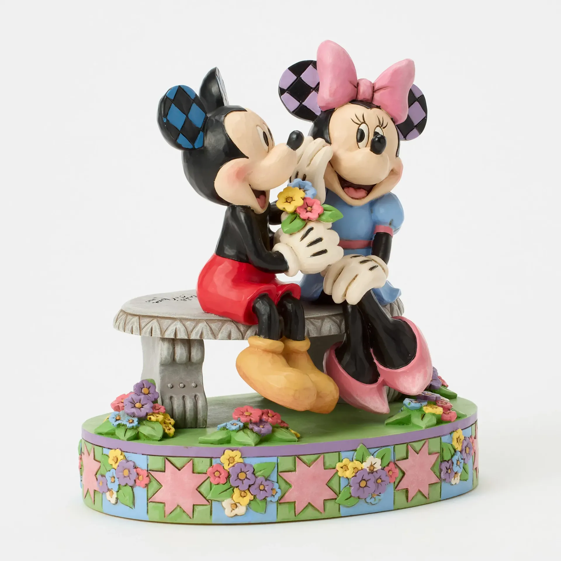 Mickey Mouse geeft bloemen aan Minnie Mouse, beiden zittend op een bankje; decoratieve sokkel.