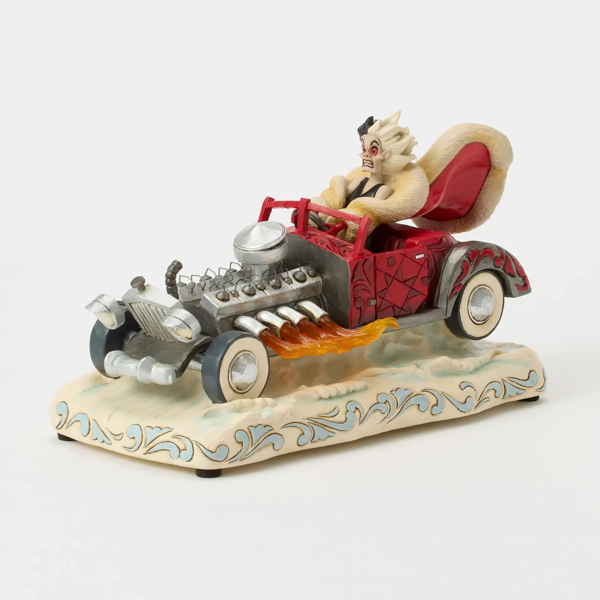 Een beeldje van een in bont gehuld wezen dat in een rode hot rod rijdt, met vlammen, op een decoratieve sokkel.