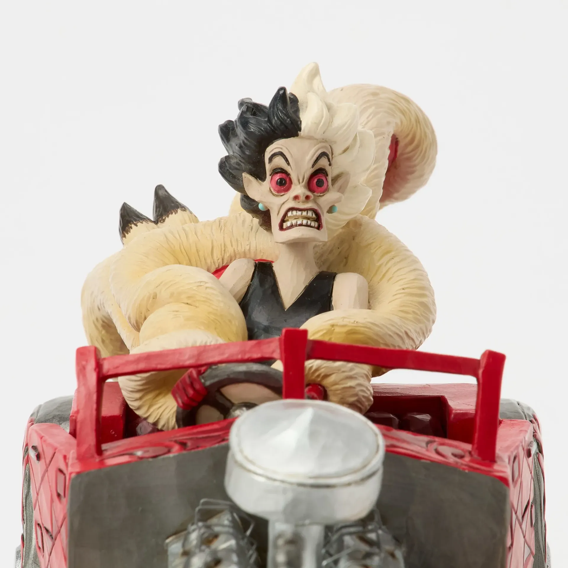 Een beeldje van een in bont gehuld wezen dat in een rode hot rod rijdt, met vlammen, op een decoratieve sokkel.