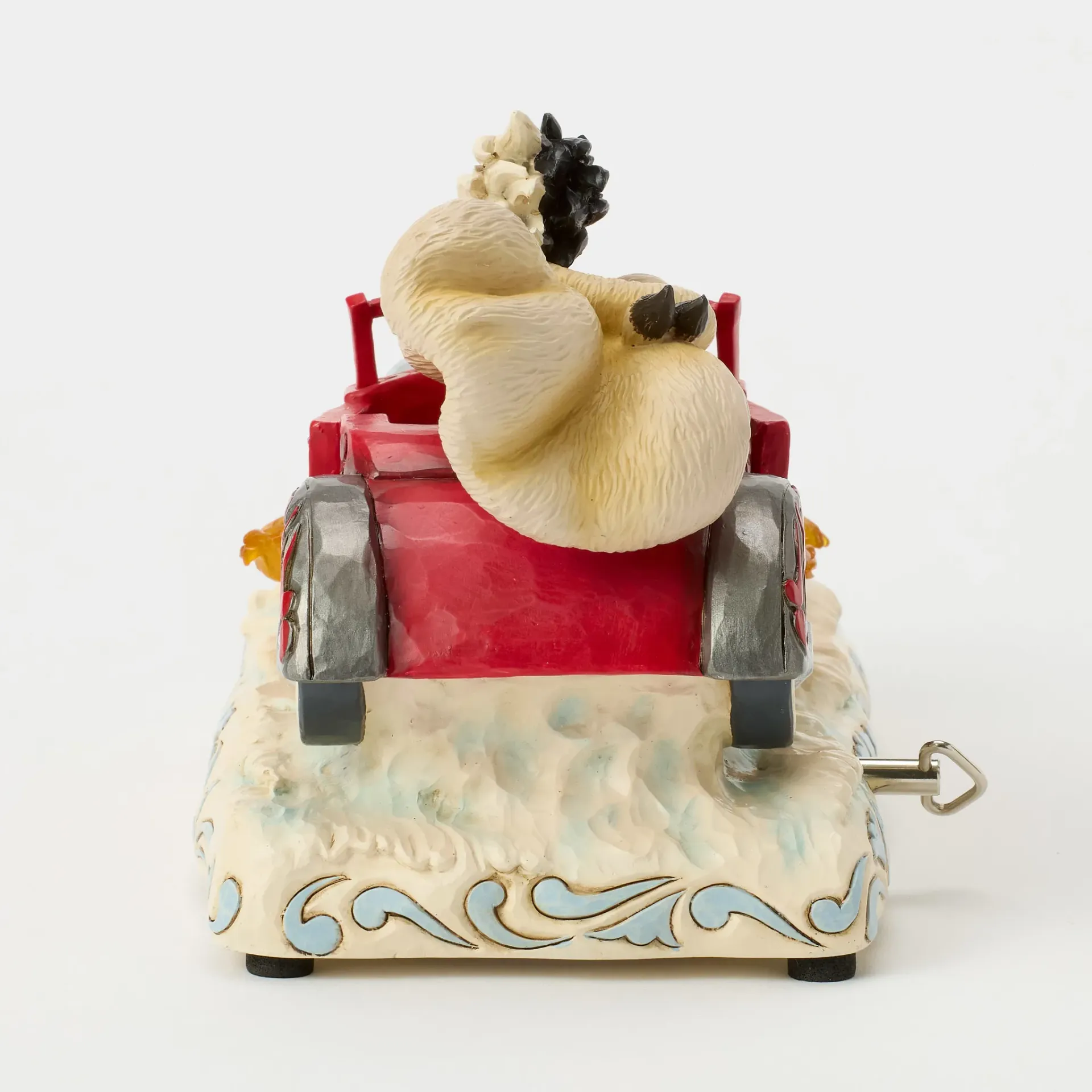 Speelgoedschaapje in een rode auto, met een witte, decoratieve voet.