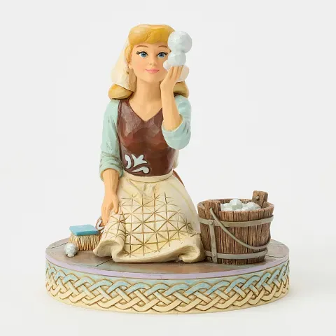 Een Assepoester-beeldje, knielend naast een emmer, die de zeepbellen bewondert. Lichtblauw, bruin en blond haar.