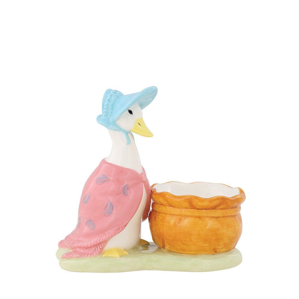 Een eendje met een blauw mutsje en een roze sjaal, naast een mandje.