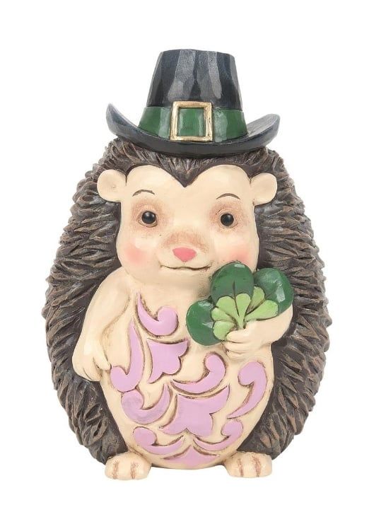 Een egelfiguurtje met een St. Patrick's Day-hoedje op, een klavertje vier in zijn hand en roze krullen op zijn buik.