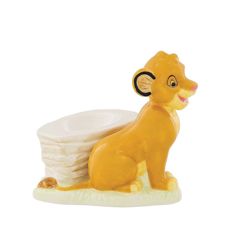 Een beeldje van Simba's welp staat naast een kleine, gelaagde rotsformatie in gele en beige tinten.