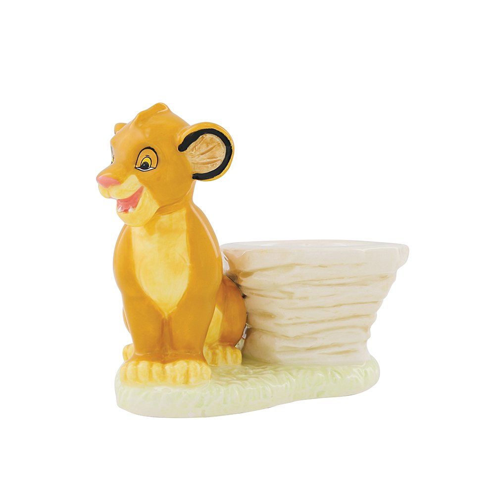 Een beeldje van Simba's welp staat naast een kleine, gelaagde rotsformatie in gele en beige tinten.