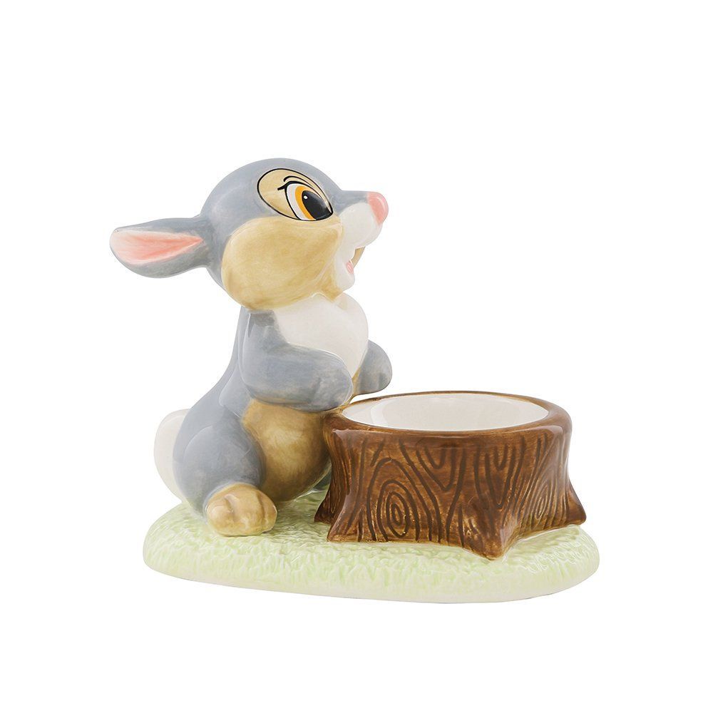 Het beeldje van Thumper staat naast een boomstronk. Het grijze konijn kijkt omhoog en glimlacht.