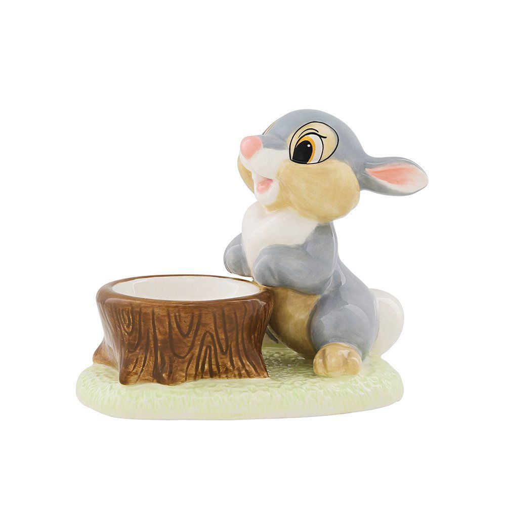 Het beeldje van Thumper staat naast een boomstronk. Het grijze konijn kijkt omhoog en glimlacht.