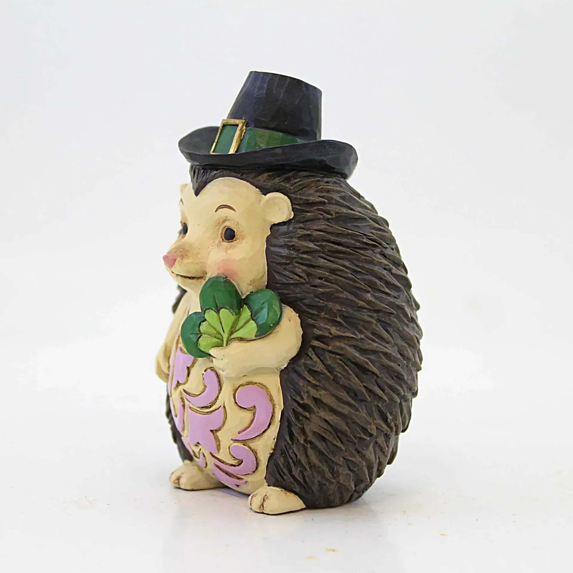 Een egelfiguurtje met een zwarte hoed, klavertjesdrie in zijn hand en versierd met roze krullen.