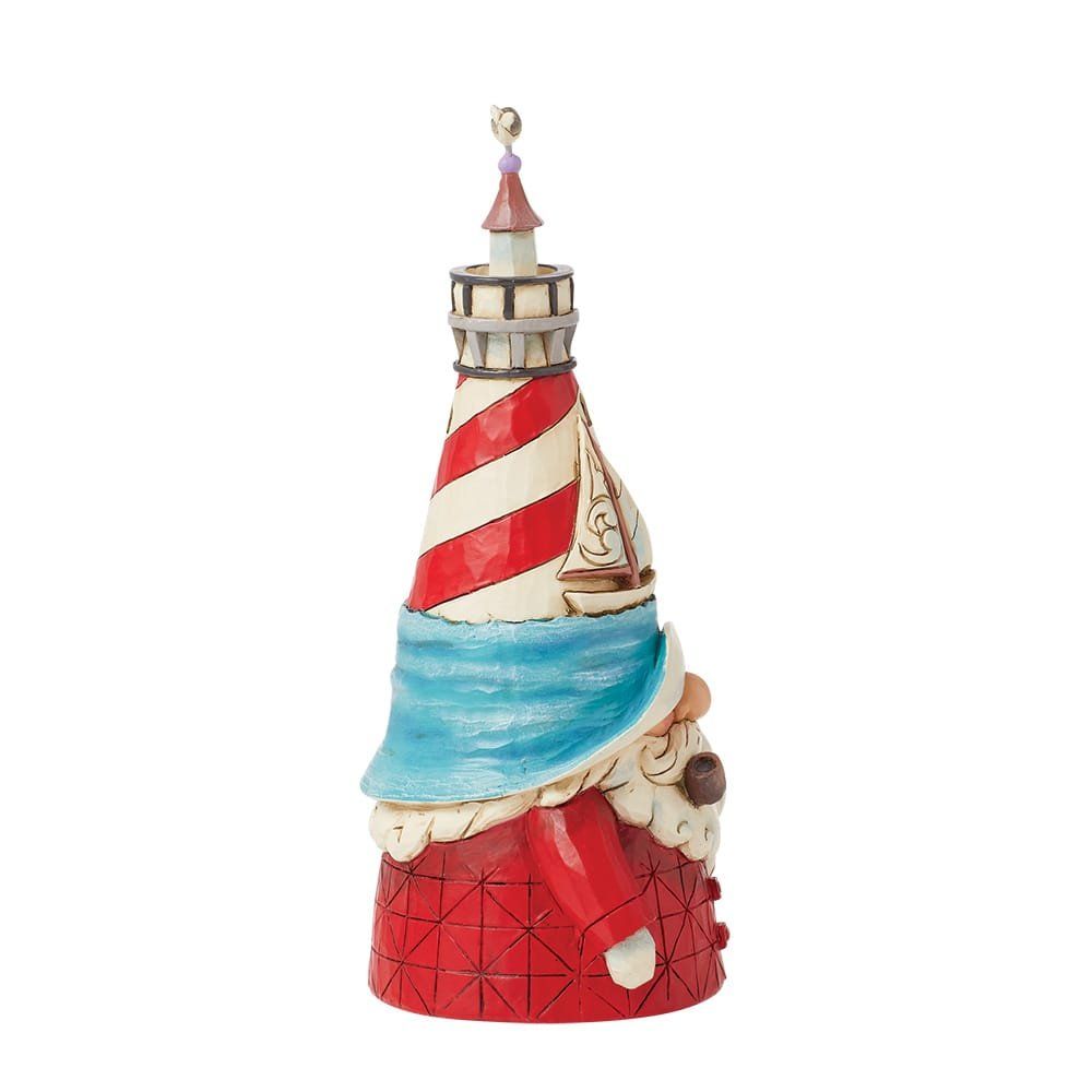 Een beeldje van een vuurtoren met rode en witte strepen, blauw water en een klein zeilbootje.
