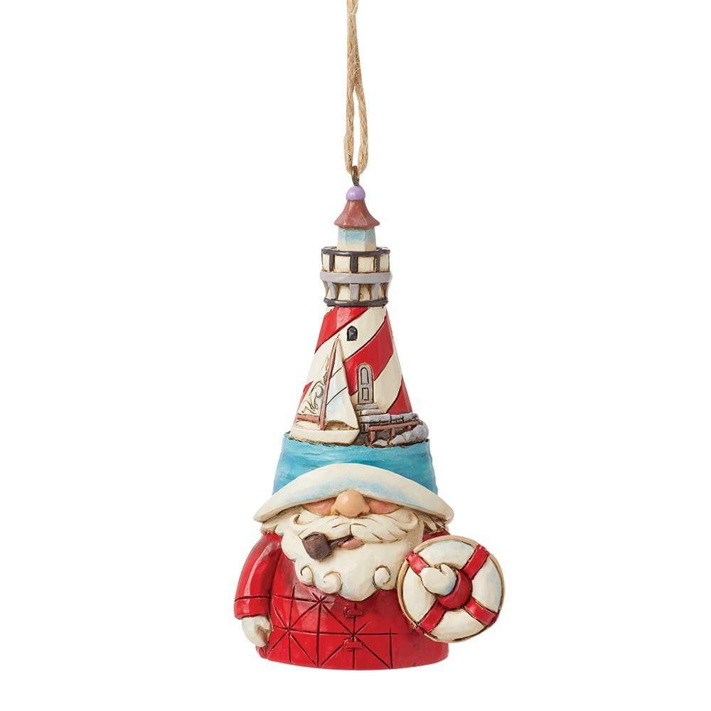 Kerstornament in de vorm van een vuurtoren met reddingsboei, in de kleuren rood, wit en blauw, met een kerstman aan de kust.