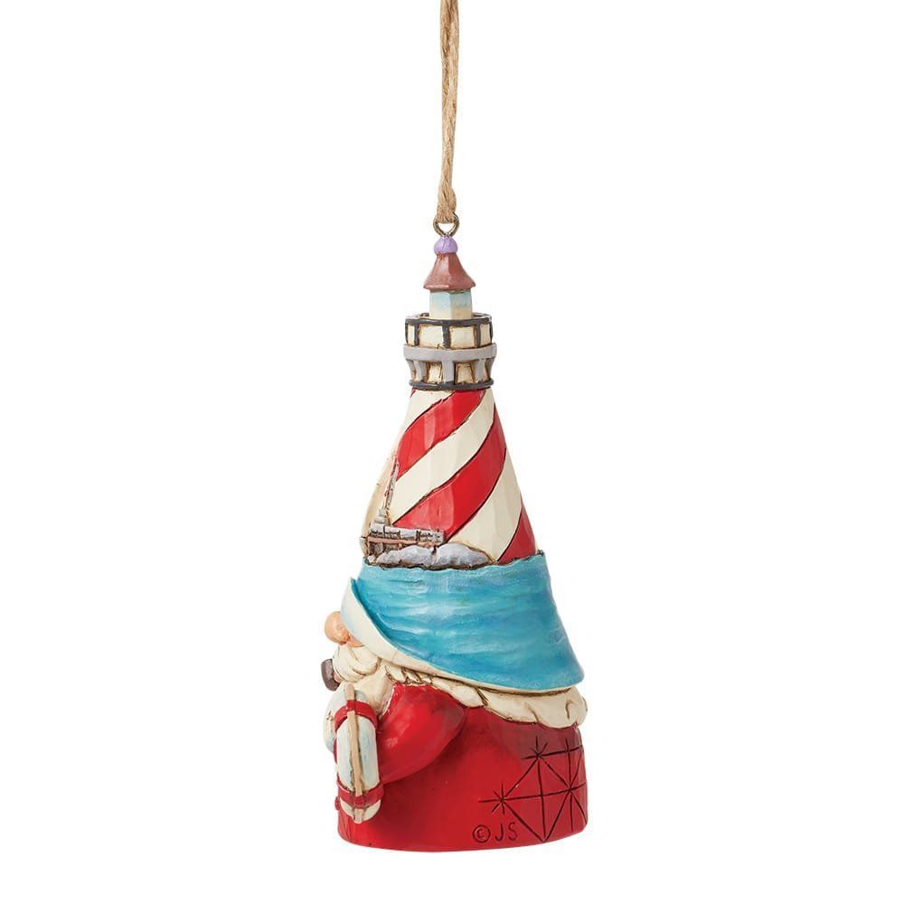 Kerstornament in de vorm van een vuurtoren met reddingsboei, in de kleuren rood, wit en blauw, met een kerstman aan de kust.