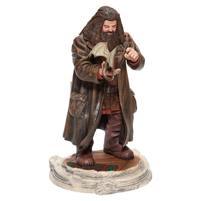 Standbeeld van Rubeus Hagrid, gekleed in een bruine jas, met een babydraak in zijn armen.