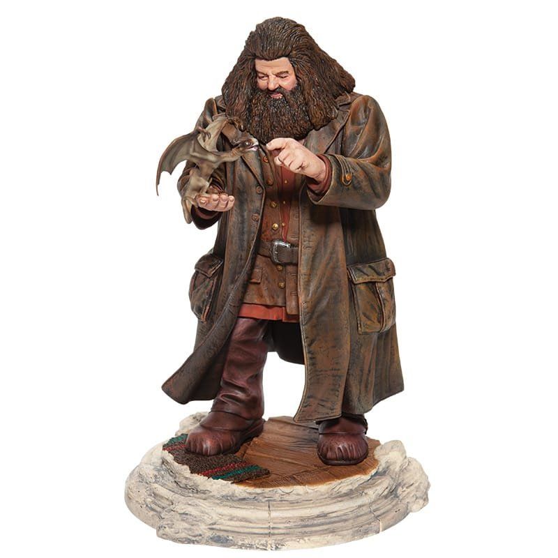 Standbeeld van Hagrid uit Harry Potter, met een babydraakje in zijn armen en gekleed in een lange bruine jas.