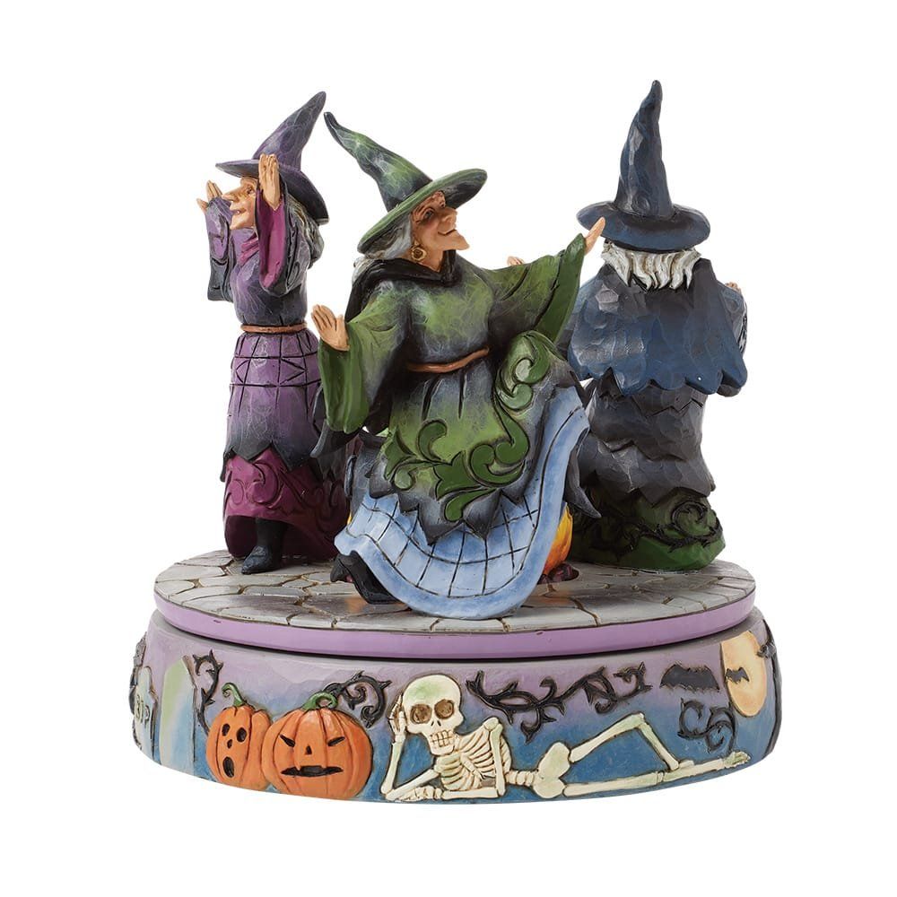 Drie cartoonheksen in kleurrijke gewaden op een sokkel met Halloween-thema.