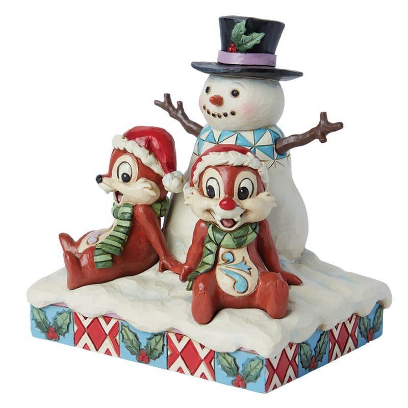 Chip, Dale en een sneeuwpopfiguurtje op een besneeuwd platform, met feestelijke mutsen en sjaals.