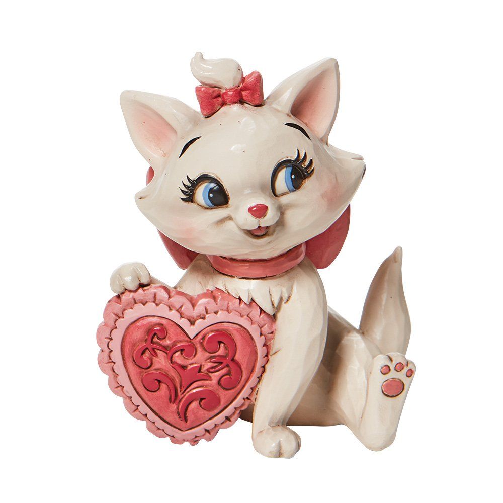 Marie, het katje, houdt een roze hartje vast en draagt een strik.