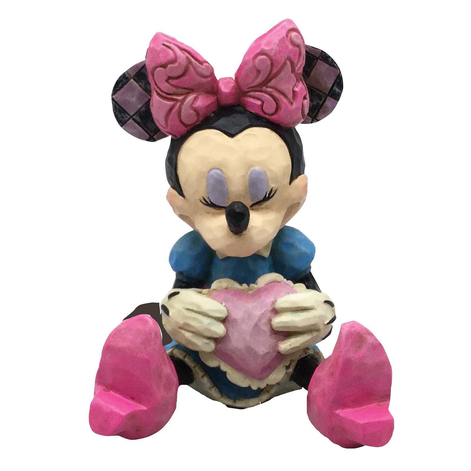Minnie Mouse-figuurtje, zittend met een roze hartje in haar hand, met gesloten ogen, gekleed in een blauwe jurk en een roze strik.