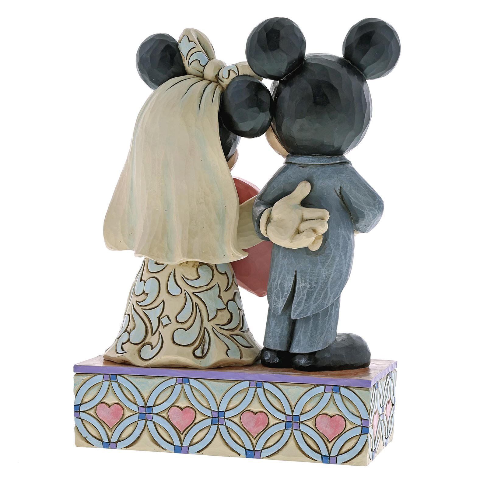 Mickey en Minnie Mouse trouwbeeldje, achterkant gezien. Ze houden een roze hartje vast en staan ​​op een versierde sokkel.