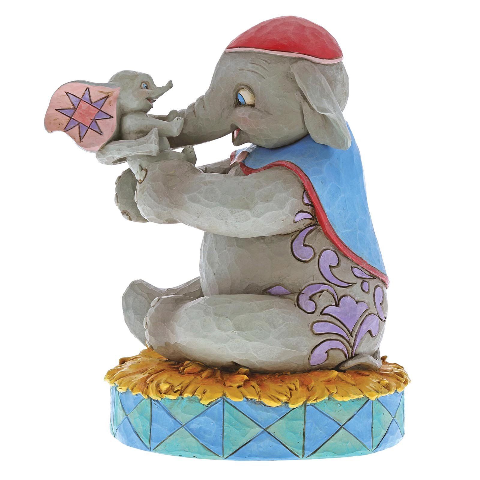 Een Dumbo-figuurtje dat baby Dumbo vasthoudt, op een geelblauwe circusvoet.