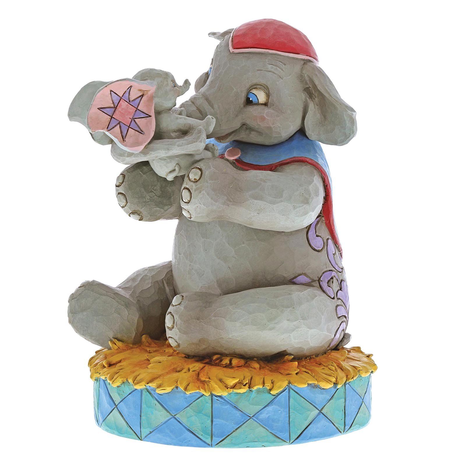 Een Dumbo-figuurtje dat een babyolifantje vasthoudt, beiden op een circuspodium.