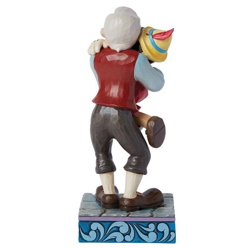 Pinocchio en Geppetto omhelzen elkaar en glimlachen; kleurrijk beeld op een decoratieve sokkel.