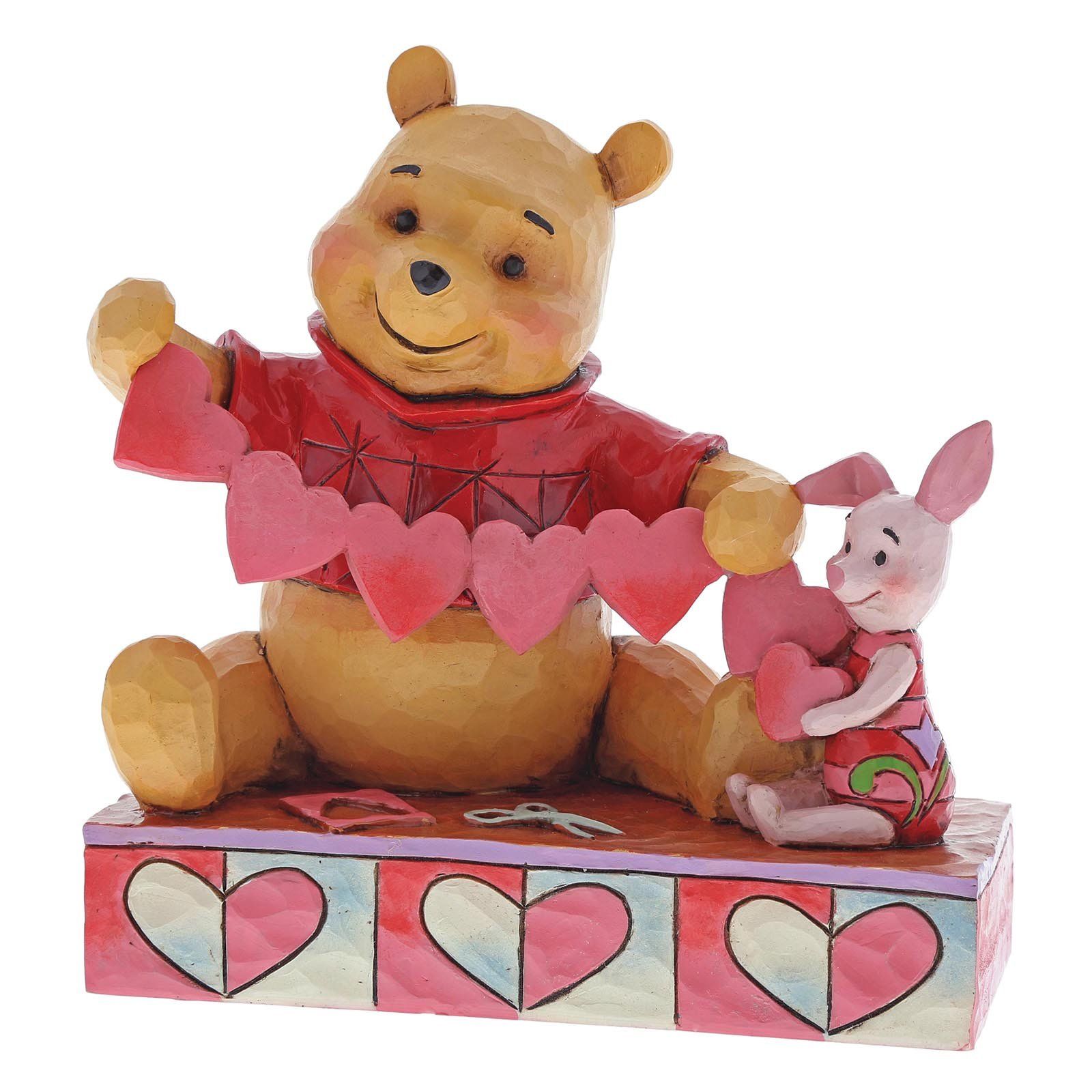Winnie de Poeh en Knorretje houden een hartjeskrans vast en glimlachen. Rood shirt, roze hartjes, kleurrijke ondergrond.