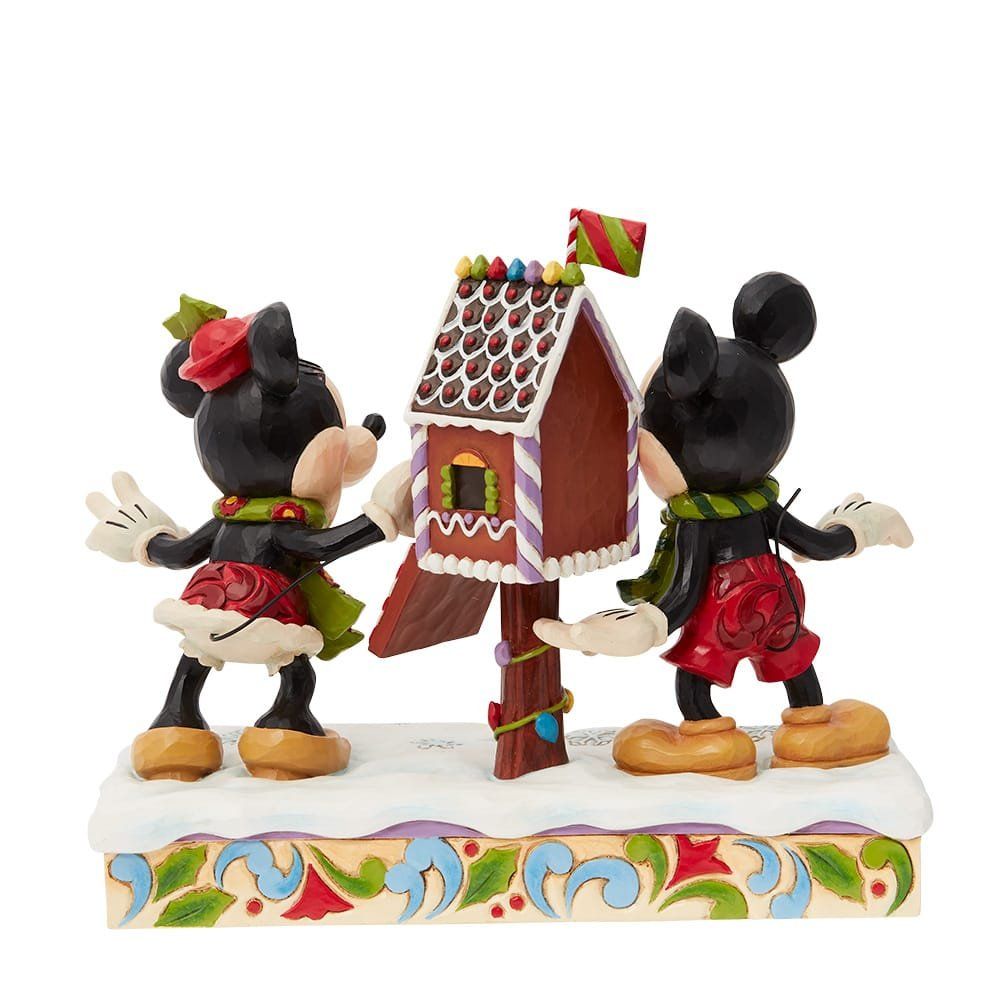 Mickey en Minnie Mouse-figuurtjes versieren een peperkoekhuisje met sneeuw en feestelijke details.