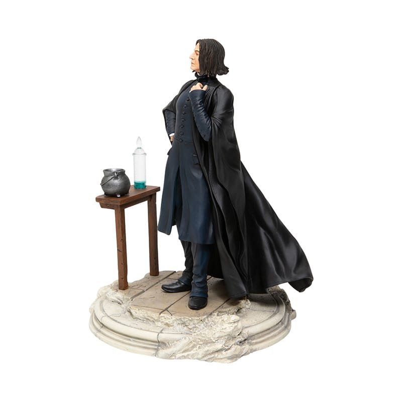 Standbeeld van Severus Snape, in mantel en gewaad, naast een tafel met een ketel en een flesje, op een stenen sokkel.